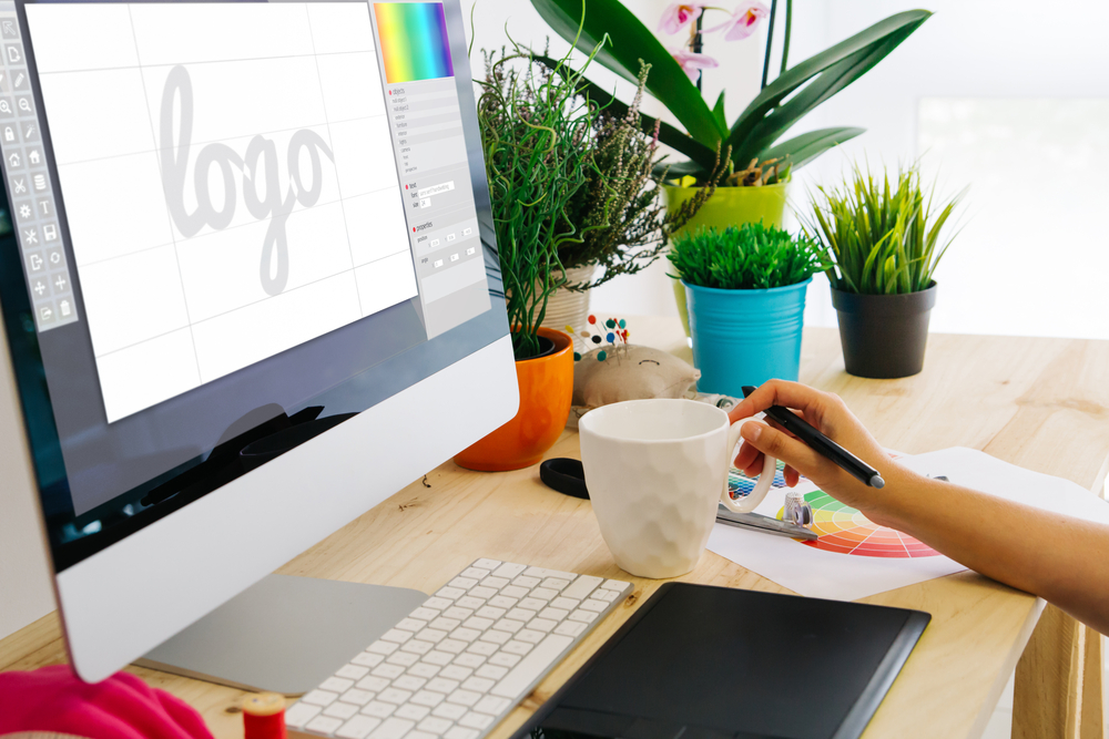 Graphic designer using pen tablet to design a logo. All screen graphics are made up.