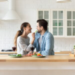 Happy millennial couple have fun celebrating in home kitchen